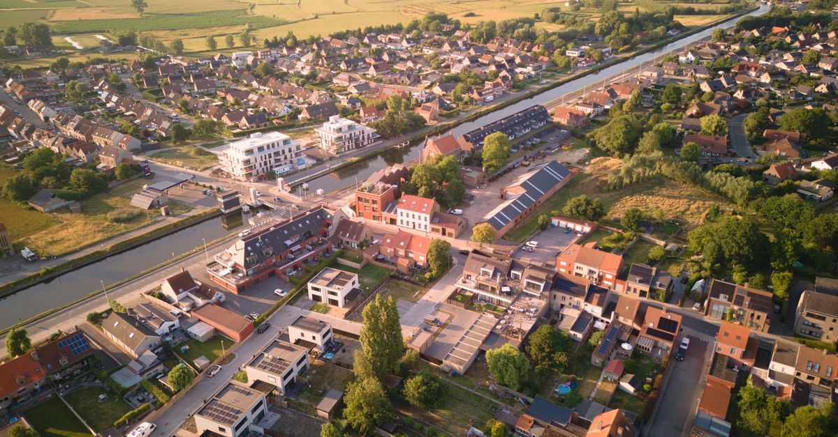 Aerial shot of Oudenburg, Belgium showcasing residential area and canal in summer light.